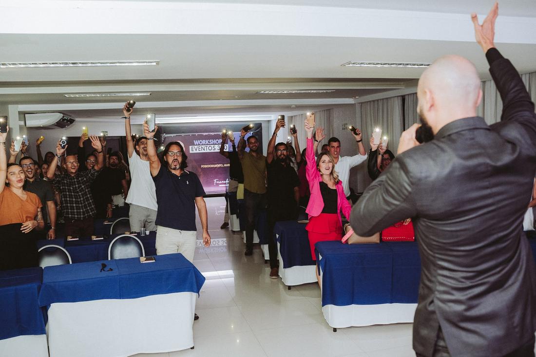 Plateia de braços levantados, com luzes de celular acesas, em workshop de eventos organizado pela Ellen Regina