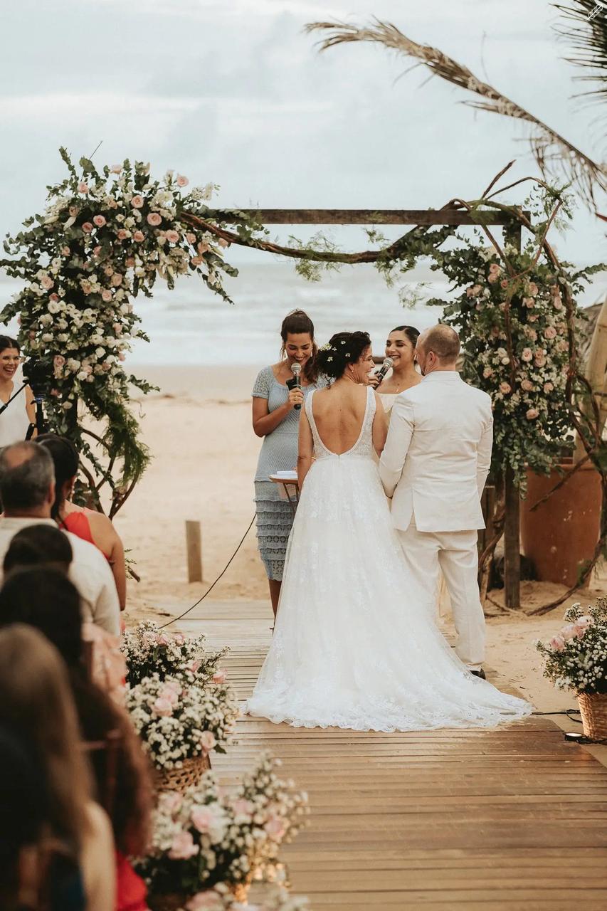 Casal diante do arco de flores na praia