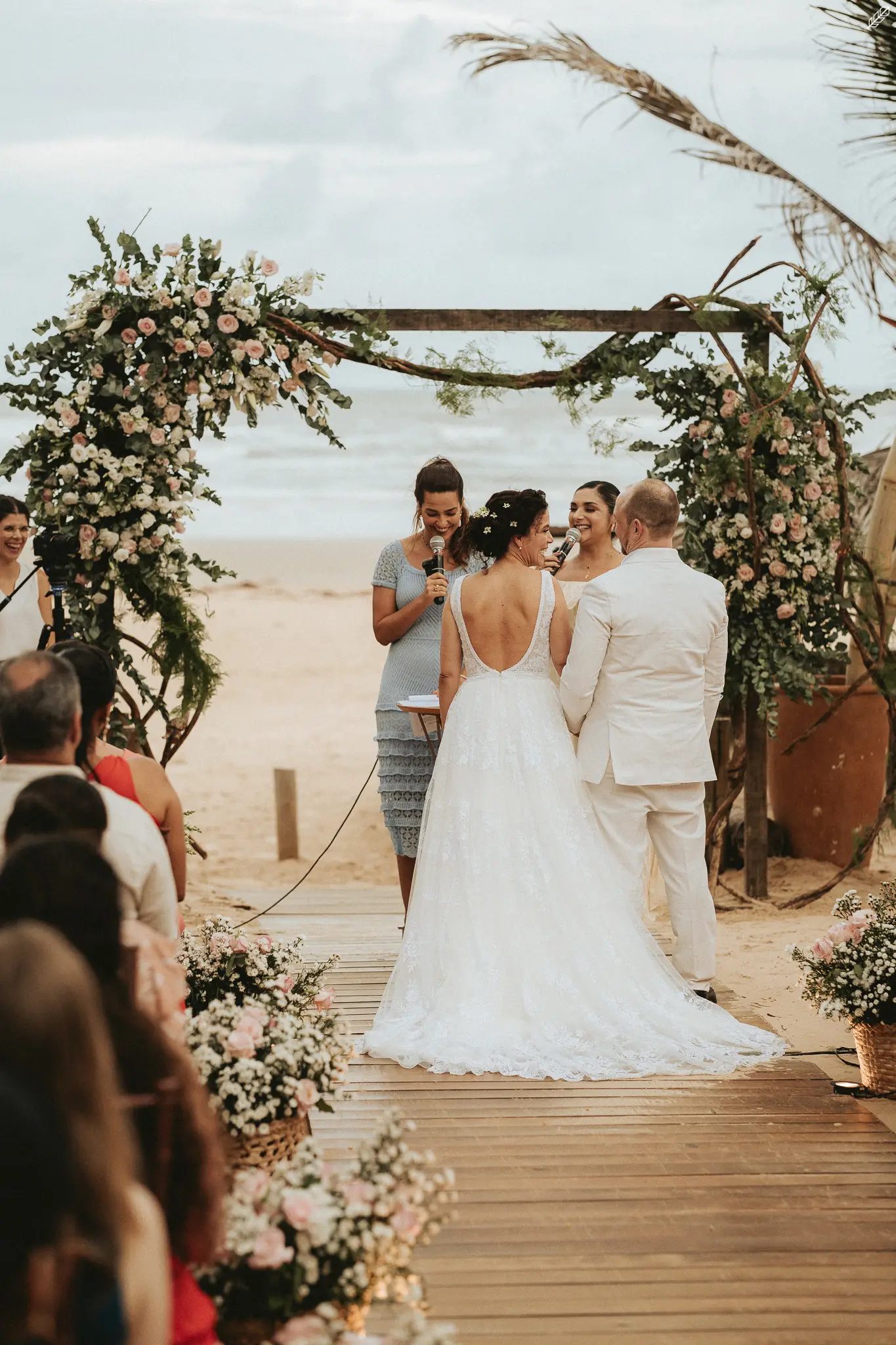 Casal diante do arco de flores na praia
