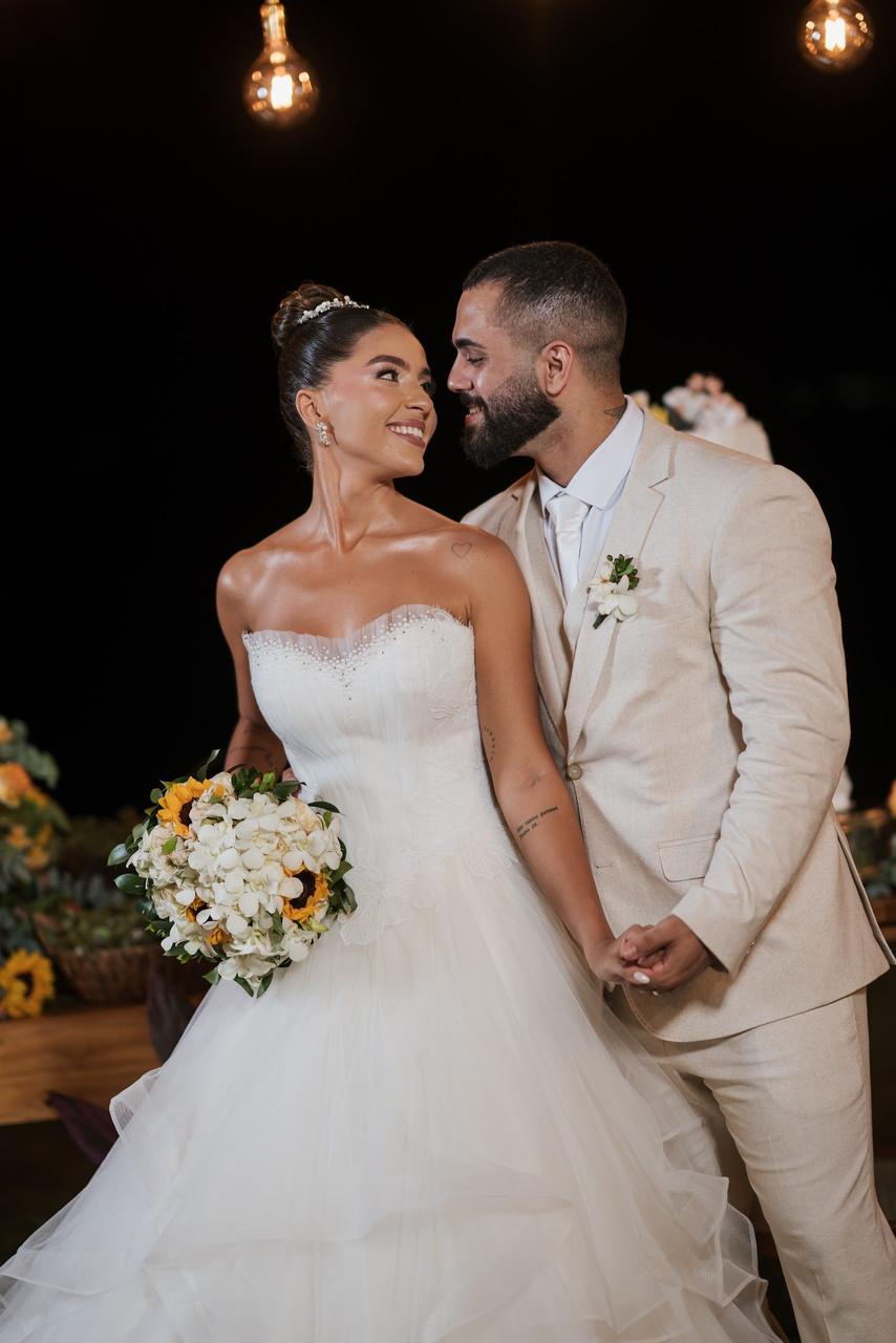 Gabi e Caio sorrindo na festa à noite